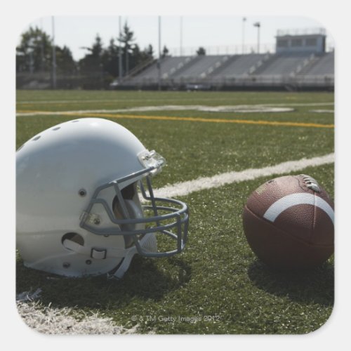Football and football helmet on football field square sticker