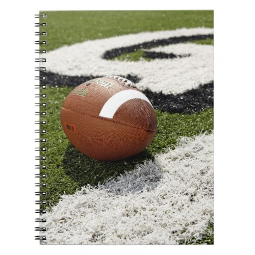 Football at goal line on football field notebook