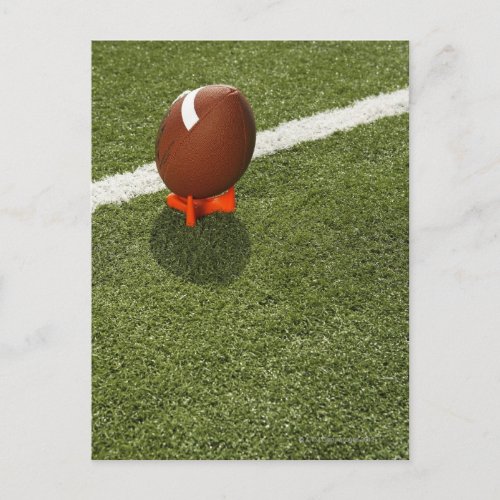 Football atop tee on football field elevated postcard