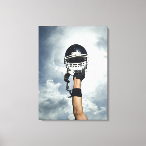 Football player holding helmet in air canvas print
