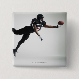 Football player leaping in mid air to catch ball button