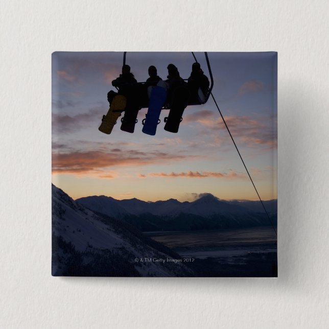 Four snowboarders are silhouetted on a ski lift button (Front)