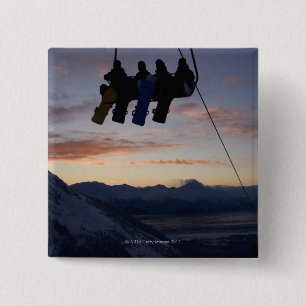 Four snowboarders are silhouetted on a ski lift button
