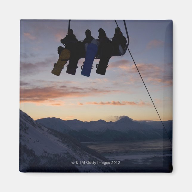Four snowboarders are silhouetted on a ski lift magnet (Front)