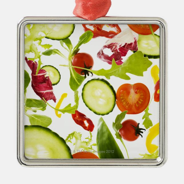 Fresh mixed salad vegetables falling to camera metal ornament (Front)