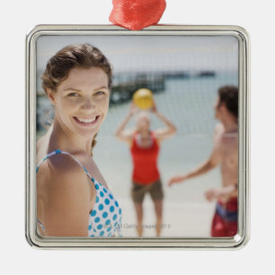 Friends playing volleyball at beach metal ornament