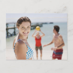 Friends playing volleyball at beach postcard