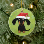 Funny Dachshund Santa Clause Wiener Dog Christmas Ceramic Ornament<br><div class="desc">A cute Dachshund lover’s Christmas ornament. Funny black and tan longhaired wiener dog puppy with long fluffy ears wearing a Santa hat. The back side of this ornament can be personalized with your text. An original cartoon weenie dog art illustration by ©Jenn Inashvili. Makes a sweet gift and treasured ornament...</div>