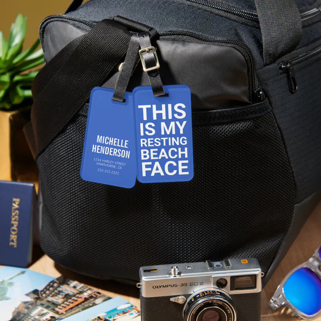 Black duffel bag with a zoomed-in viewpoint of the blue and white luggage tag. A digital camera and photos are in the bottom corners to finish off the aesthetic nicely.