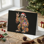 Funny Santa Bigfoot with Christmas Lights Holiday Card<br><div class="desc">This funny holiday design features Bigfoot wearing a Santa hat and sunglasses while wrapped in colorful Christmas lights on a black background. The playful pose, rock hand gesture, and bright festive details give the artwork a bold and humorous seasonal look. The dark backdrop helps the lights and character stand out...</div>