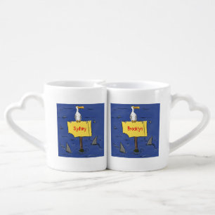 Funny sea bird circled by sharks cartoon coffee mug set