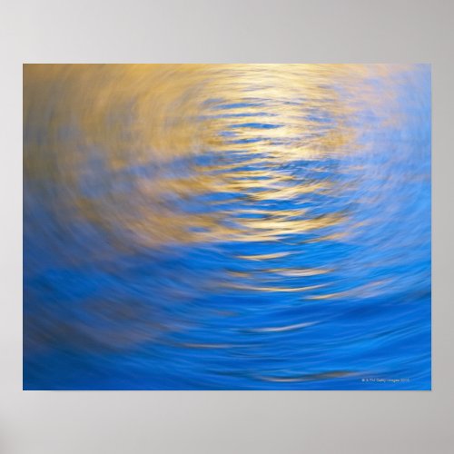 Gently rippled water reflecting gold and blue poster