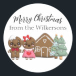 Gingerbread People Merry Christmas Custom Name Classic Round Sticker<br><div class="desc">These custom holiday sticker labels feature a cute Christmas theme. An image of a gingerbread man and lady are pictured standing in front of a cute little gingerbread house and pine trees. A sample "Merry Christmas" greeting is pictured above the family, followed by a sample family name. You can personalize...</div>