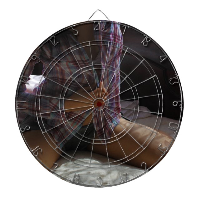 Girl in Flannel Shirt kneeling on a Bed Dartboard With Darts (Front)