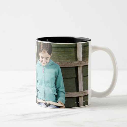 Girl sitting and reading book near vine Two_Tone coffee mug