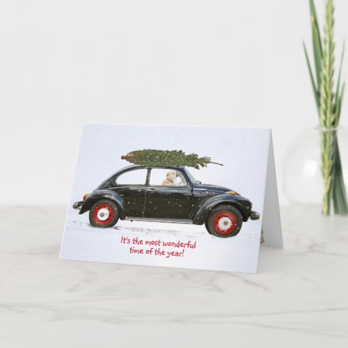Golden retriever in old car with holiday tree card