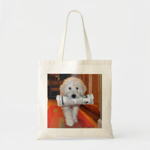 Goldendoodle carrying newspaper toy tote