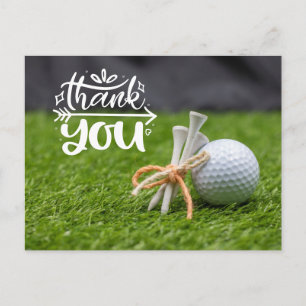 Golf ball and tee are on green grass thank you pos postcard