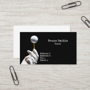Golf ball on pin next to hole black background business card