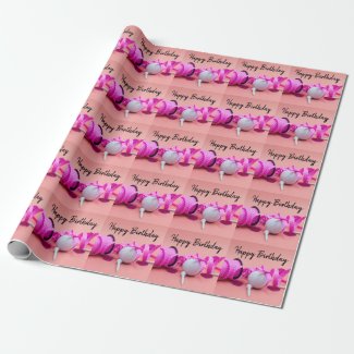 Golf ball with pink polka dot ribbon on pink wrapping paper