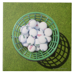 Golf balls in a basket sitting on short green tile