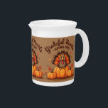 Grateful Hearts Thanksgiving Turkey Beverage Pitcher<br><div class="desc">This charming Thanksgiving design features an adorable cartoon turkey with vibrant orange, red, and brown tail feathers perched atop a trio of plump pumpkins. Surrounded by whimsical falling hearts, autumn leaves, and warm seasonal colors, the artwork is framed by the joyful phrase “Grateful Hearts Gather Here” in bold, playful lettering....</div>
