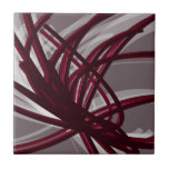 Gray & Burgundy Abstract Ribbons Ceramic Tile<br><div class="desc">Modern artistic design featuring burgundy wine colored ribbons with white accents on a gray background. Designed with vector graphics, you can create your own customized throw pillow by changing the background and border colors. To create your personalized design, select “customize” and navigate to the layers section to view the images...</div>