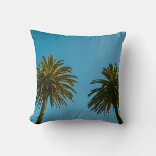 Green palm tree under blue sky in the morning throw pillow