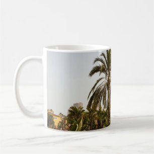 Green palm trees near brown concrete building in t coffee mug