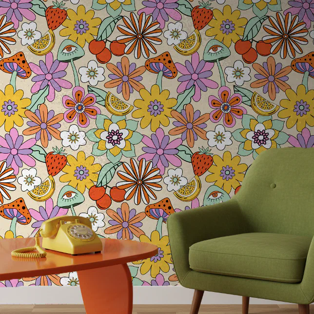 A brown table with a yellow old-fashioned telephone next to a green chair. There is a bright and colorful 70s-style floral and fruit-themed wallpaper on the wall in the background.
