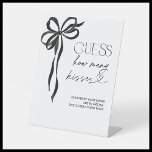 Guess How Many Kisses Black Bow Bridal Shower Pedestal Sign<br><div class="desc">Designed for hosts who appreciate refined details, this Guess How Many Kisses game sign is a stunning way to invite guests to participate in a sweet and stylish challenge. With its elegant black ribbon illustration and graceful typography, this piece sets the tone for a polished and thoughtfully curated bridal shower...</div>