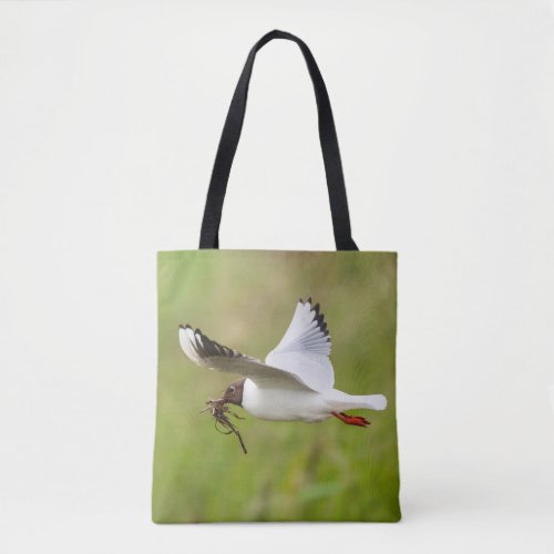 Gull flying with nesting material tote bag