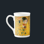 Gustav Klimt The Kiss Bone China Mug<br><div class="desc">Bone China Mug featuring Gustav Klimt’s oil painting with gold leaf The Kiss (1908). A man and woman,  wearing brilliant golden colors,  lovingly embrace and kiss in a field of flowers. A great gift for fans of Art Nouveau and Austrian art.</div>