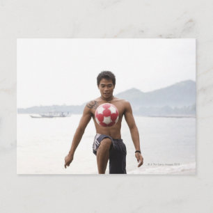 Guy playing football on beach postcard