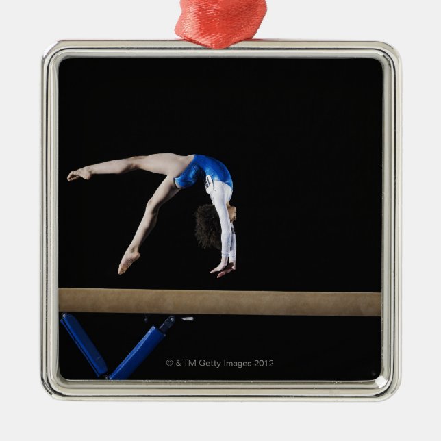 Gymnast (9-10) flipping on balance beam, side metal ornament (Front)