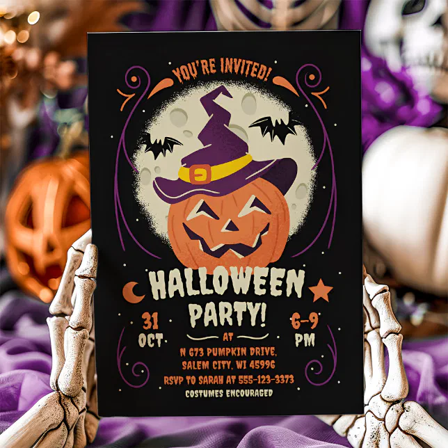 A Halloween-themed card with skeletal hands seen holding it, and set against a blurred background of various Halloween décor.