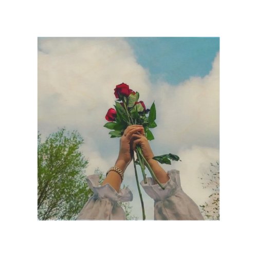 Hands Holding Red Roses Against a Blue Sky Wood Wall Art