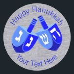 Hanukkah Dreidels In Blue Cheerful Kids Design Classic Round Sticker<br><div class="desc">Use these fun round Hanukkah stickers as party favors, to dress up a gift package, to seal envelopes or anything else your DIY self can imagine. The double Dreidel design in white and bright blues is my original artwork so these Chanukah stickers are one-of-a-kind. Set on a faux bling silver...</div>