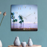 Hawaii Palm Tree Purple Landscape Photo Stylish Square Wall Clock<br><div class="desc">Appreciate the beauty of nature whenever you check the time on this blue and purple softly lit photography wall clock of palm trees blowing in the Hawaiian breeze against a mountain backdrop. Your choice of a round or square clock face. Makes a great housewarming gift! You can easily personalize this...</div>