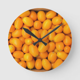 Heap of orange kumquats in cardboard box round clock