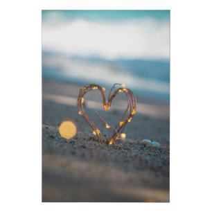Heart-shaped lights in sand on a beach faux canvas print