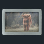 Highland cow calf autumn grass field belt buckle<br><div class="desc">Highland cow calf autumn grass field photograph. Stunning young calf of highland Scottish cattle on an autumn grassy field with muted colors. Beautiful dark hairy orange coat contrasting with light yellow green grass and trees in bokeh in background.</div>