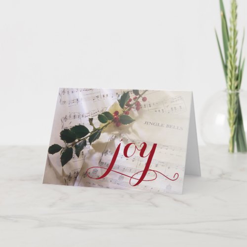 Holly branch on top of sheet music for Christmas Holiday Card