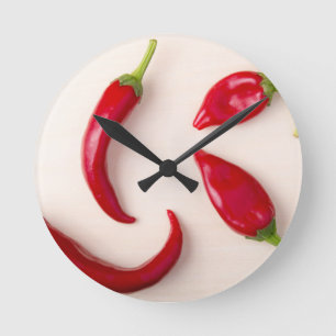 Hot red chili peppers on a light wooden board round clock