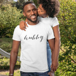 Hubby Modern Black Script White Mens T-Shirt<br><div class="desc">Clean and classic, this white tee features "Hubby" in sleek modern black script for a polished newlywed statement. The hand-lettered calligraphy pops against the crisp white background, making it ideal for honeymoon photos, engagement parties, and casual everyday wear. A thoughtful gift for the groom-to-be or newly married husband. Pairs with...</div>