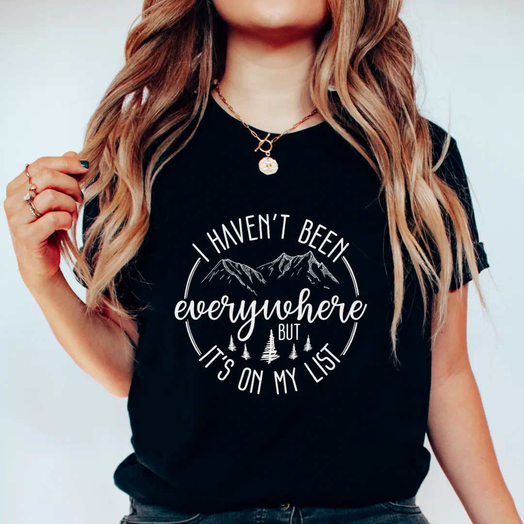 Focused shot on a blonde girl wearing a customized black tee. The background is plain and simple.