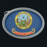 IDAHO STATE FLAG BELT BUCKLE<br><div class="desc">The flag of the state of Idaho consists of the state seal on a field of blue.
The words "State of Idaho" appear in gold letters on a red and gold band below the seal.</div>