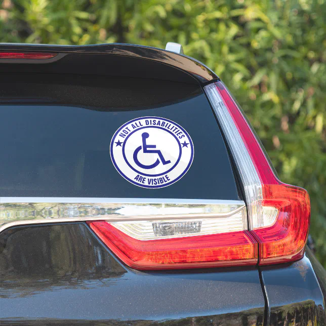 A disability bumper sticker is shown on a car window.