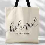 Ivory Cream Bridesmaid Modern Script Tote Bag<br><div class="desc">Show your appreciation to your bridal party with this stylish ivory cream bridesmaid tote bag. Featuring modern script and customizable with your bridesmaid's name, this tote bag is both practical and elegant. The soft color and chic design make it perfect for carrying wedding day essentials or everyday items. This personalized...</div>