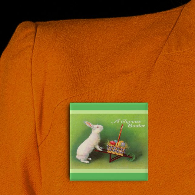 Joyous Easter Rabbit Basket Eggs Pinback Button (Joyous Easter white rabbit pushing wheelbarrow coloured eggs on green pin back button.)